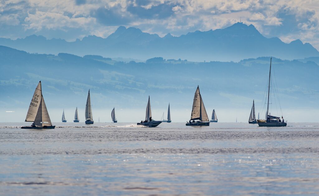 Lots of yachts with their sails up, on calm waters, with beautiful views behind. Your RYA Day Skipper ticket could take you here.